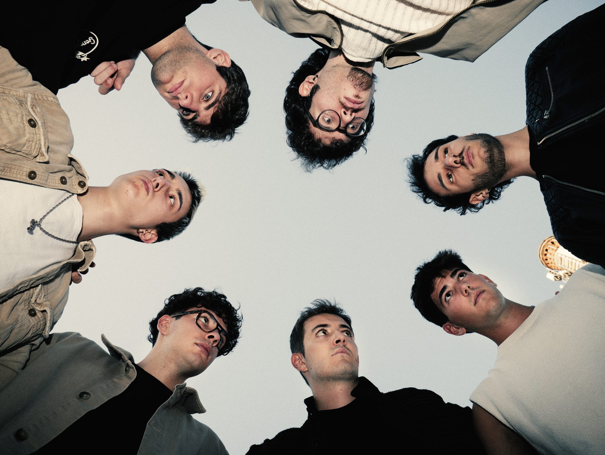 The band in a circle looking down at the camera